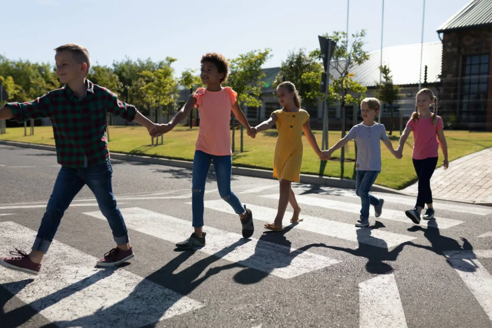Kids holding hands while crossing a street together.